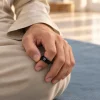 Main portant la bague de dhikr connectée, le pouce posé dessus pour compter