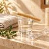 Bâton de siwak naturel posé dans un verre sur une étagère en travertin